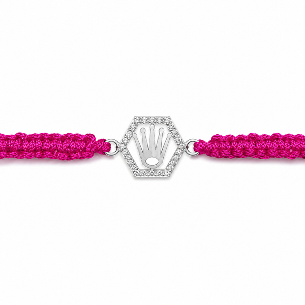 A bright pink braided cord bracelet with a silver-tone hexagonal hamsa hand charm encrusted with small clear stones, shown on a plain white background.