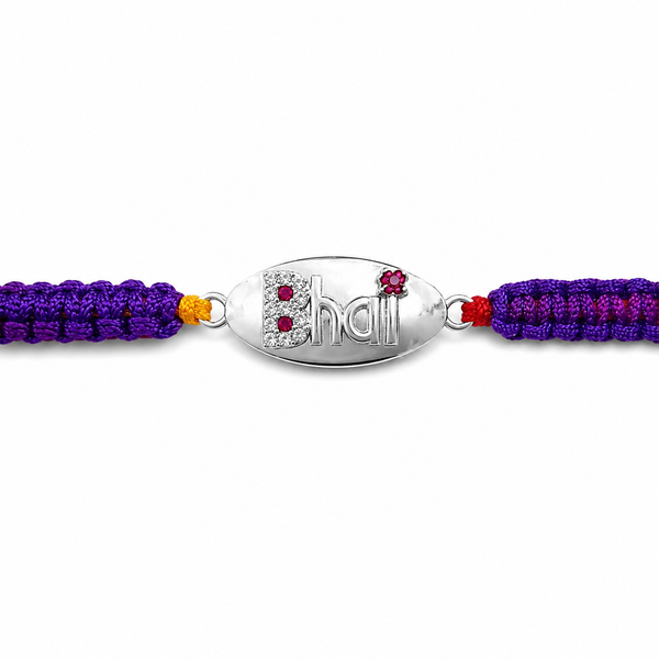 A silver oval charm bracelet featuring the word 'Bhall' in stylized lettering, embellished with small red and clear rhinestones, flanked by purple and magenta braided cords with a small yellow accent on a white background.