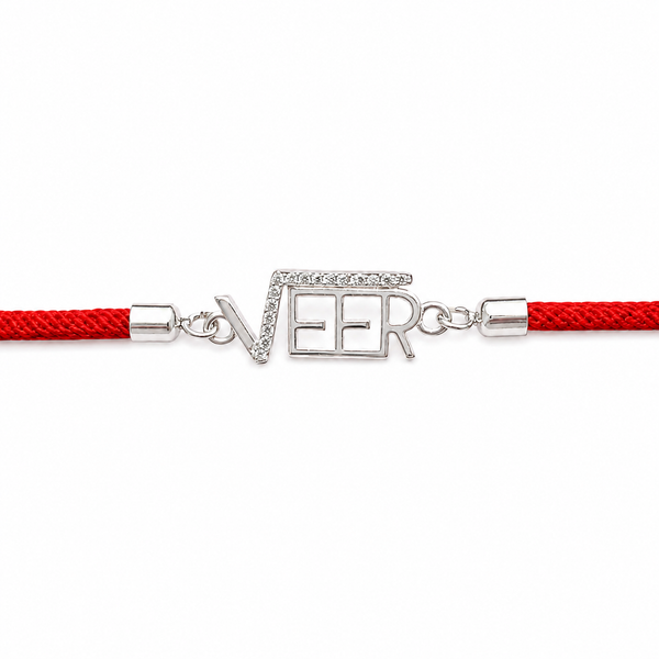 A red braided cord bracelet with a silver-tone 'NEER' nameplate charm embellished with small clear stones, shown on a plain white background.